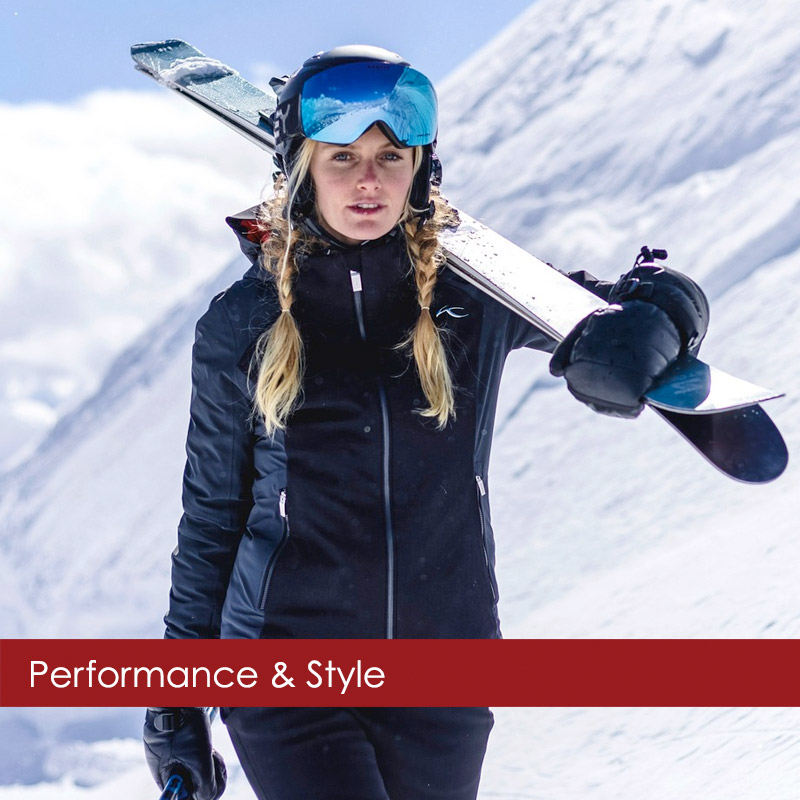 Woman carrying skis in Aspen wearing a designer ski jacket from KJUS